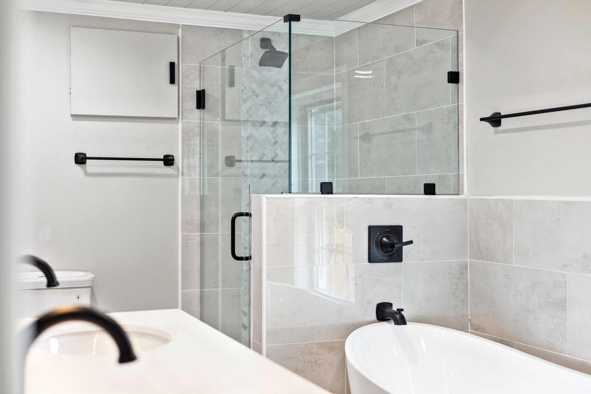 Sleek minimalist bathroom featuring a modern glass shower and elegant bathtub in Lakewood, CA